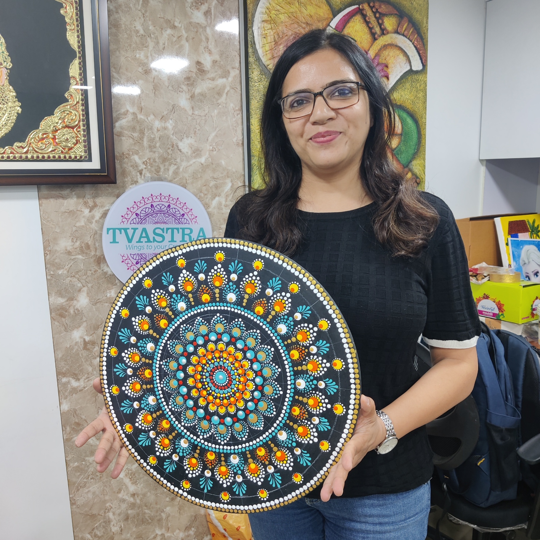 Dot mandala artwork on black canvas with turquoise and saffron patterns